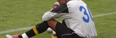 soccer player sitting on field with head down