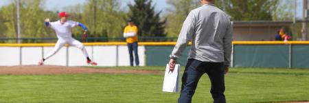 a baseball coach watches the player pitch
