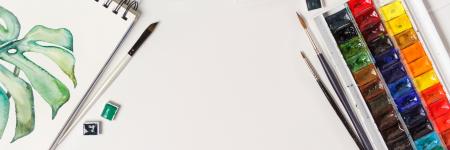 a painting of a palm tree next to paintbrushes and watercolors